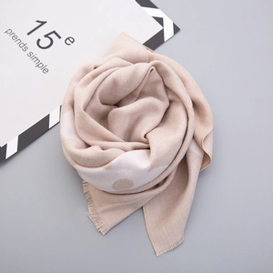 Detailed view of soft beige cashmere-like scarf with white polka dots and fringe edges