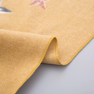 Gros plan sur l'écharpe enfant jaune gingembre avec motif étoile et coutures de précision