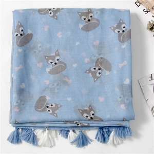 Close-up of light blue scarf with fox patterns, pink hearts and cotton tassel fringe