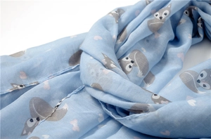 Detailed close-up of light blue scarf with fox head pattern and fine cotton linen weave