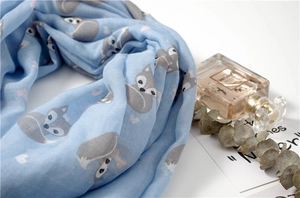 Detail of light blue scarf with fox and heart patterns, soft fabric in a cozy setting