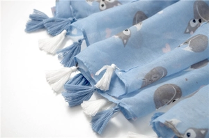Detail of light blue scarf with cartoon fox print and decorative fringe tassels
