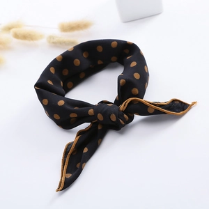 Detail of a black and brown polka dot satin scarf tied in a stylish knot on white background