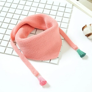 Détail d'une écharpe triangle en tricot rose avec des pompons de couleur vert menthe