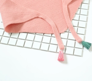 Détail d'une écharpe en maille rose avec des glands colorés et tissage doux