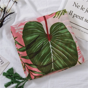 Detailed macro view of tropical palm leaf print on pink cotton linen scarf with green tassels
