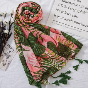 Detail of tropical leaf print scarf with green tassels on elegant white background