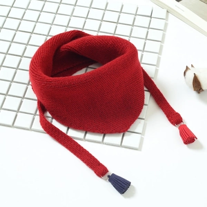 Détail d'une écharpe rouge en tricot avec texture douce et glands colorés pour enfants