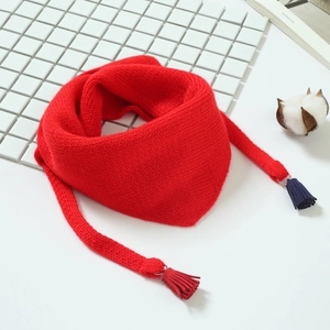 Détail d'une écharpe en maille rouge pour enfants avec pompons rouge et bleu