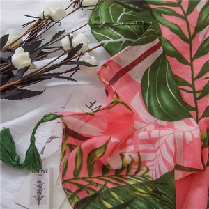 Detail of tropical leaf print on pink cotton linen scarf with woven green tassels