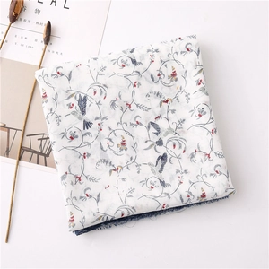 Detail of hummingbird print and tassel edges on soft off-white cotton linen shawl