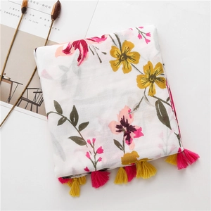 Close-up of white floral cotton linen scarf featuring pink yellow blossoms and tassels