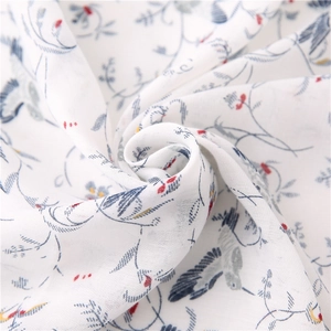 Close-up of soft cotton scarf with blue vine patterns, birds and tassel details