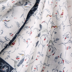 Detailed macro view of ivory linen scarf with navy floral vine and hummingbird prints