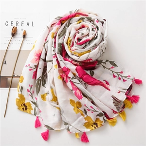 Detailed view of floral scarf with pink tassels rolled into a flower shape on white desk