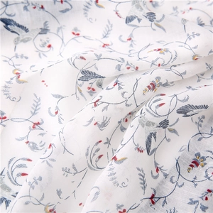Macro detail of breathable white cotton scarf fabric featuring vintage bird and floral patterns