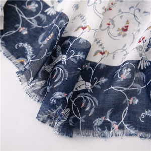 Detail of blue and white scarf with floral bird prints and frayed fringe edges