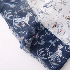 Detail of blue and white scarf featuring intricate bird and floral vine patterns