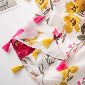Detailed close-up of floral print scarf with bright yellow and pink tassel fringe accents