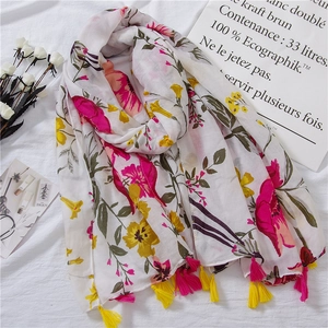 Detailed close-up of a floral cotton linen scarf with pink tassels on white fabric