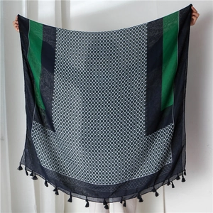Detail of a patterned scarf featuring white circular motifs, fringes and contrast panels
