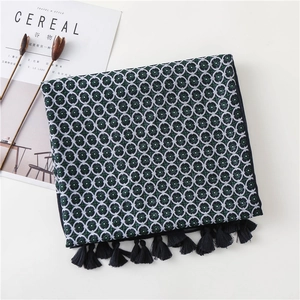 Macro view of geometric floral pattern and black tassels on a navy blue silk scarf