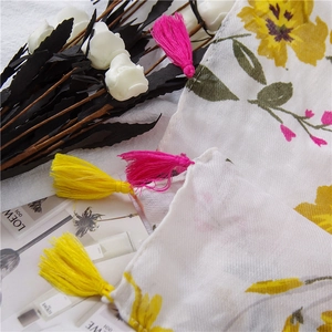 Detail of vibrant yellow flower print on white fabric with colorful tassels decoration