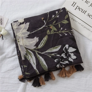 Close-up of floral print cotton linen scarf with elegant dark base and decorative tassels