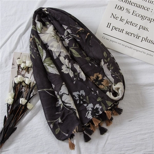 Detail of dark floral cotton scarf with tassel trim and elegant botanical patterns