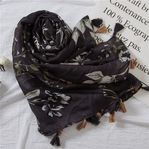 Detail of floral print scarf with tassel edge on white textured background