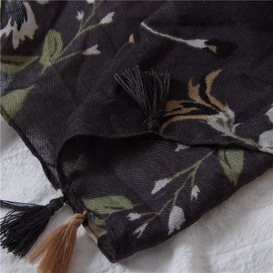 Close-up of floral print patterns and handcrafted tassel edges on the cotton linen scarf