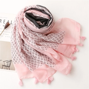 Detail of pink and grey patterned scarf with elegant tassels on a minimalist white surface