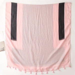 Close-up of pink scarf with black geometric patterns and delicate fringe tassels detail