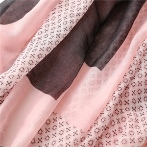 Detail of pink and grey silk scarf featuring elegant cross patterns and soft fabric texture