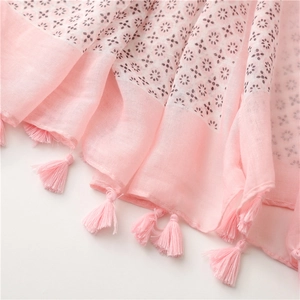 Detailed view of pink floral print scarf fabric texture with decorative fringe edges