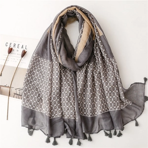 Close-up of elegant floral print scarf with gray fringe tassels and lifestyle props