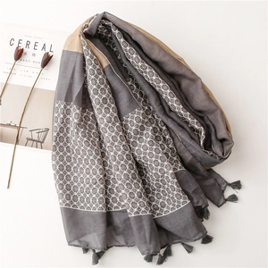 Detail of grey and beige patterned scarf with soft tassels on a clean white background