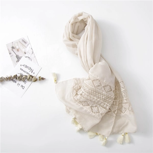 Close-up of cream scarf featuring elegant lace embroidery and tassel fringe detail