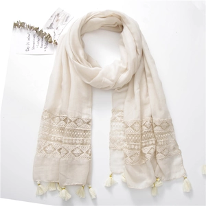 Close-up of elegant beige scarf featuring intricate lace floral embroidery and white tassels