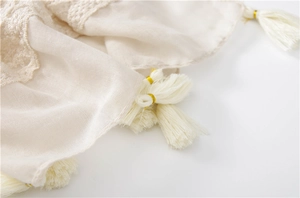Close-up of elegant cream scarf tassels with gold thread details and woven texture