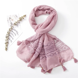 Detailed flat lay of pink scarf with lace embroidery, tassels and eucalyptus leaves
