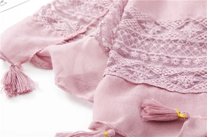 Detail of pink scarf showing floral lace embroidery and tassels with gold thread