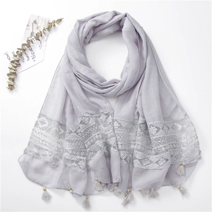 Detail view of light purple scarf with floral lace embroidery and golden bead tassels