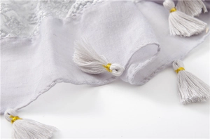 Macro shot of light purple scarf detailing with intricate gold-wrapped fringe tassels