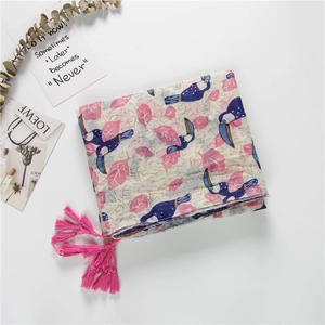 Detail of blue pelican and pink leaf print scarf with fringe tassels on white cotton fabric
