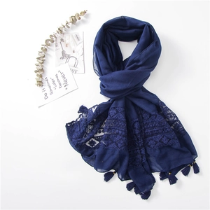 Detail of dark blue scarf featuring elegant lace embroidery and handmade fringe tassels