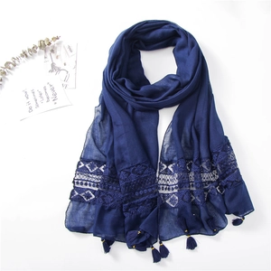 Detail of dark blue scarf featuring delicate lace embroidery and fringe tassel trim