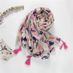 Detail of tropical toucan print scarf with pink leaf patterns and bright tassels