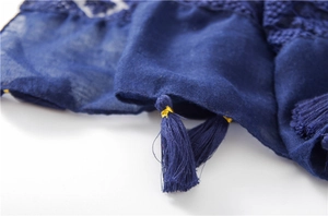 Detailed macro view of navy blue linen shawl with gold-bound fringe and tassel trim