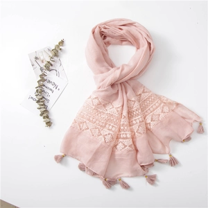 Close-up of pink linen scarf featuring geometric lace embroidery and soft fringe tassels